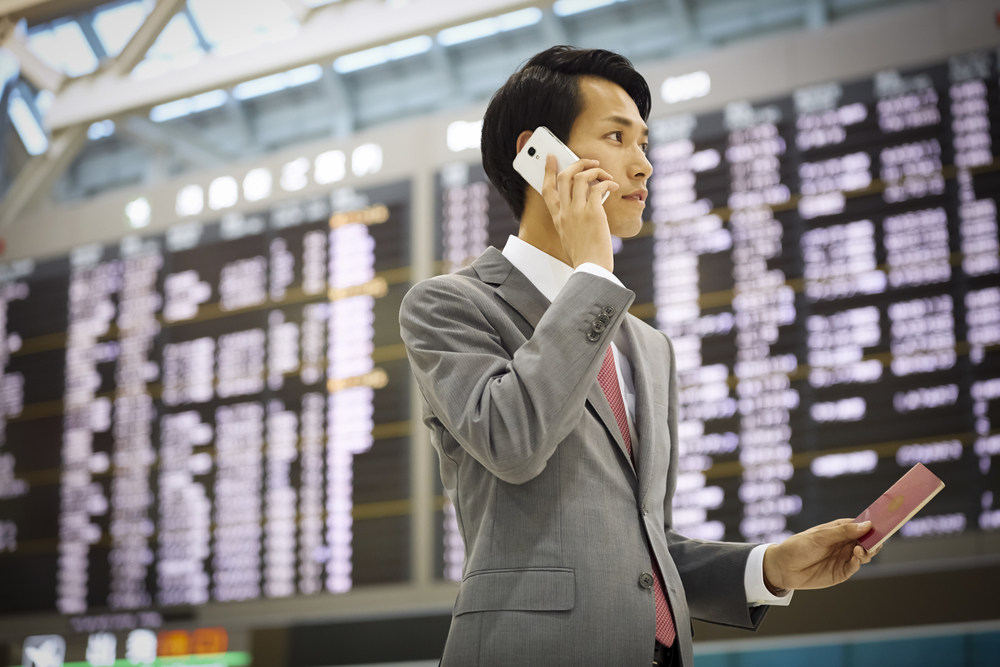 空港で電話をする海外出張のビジネスマン