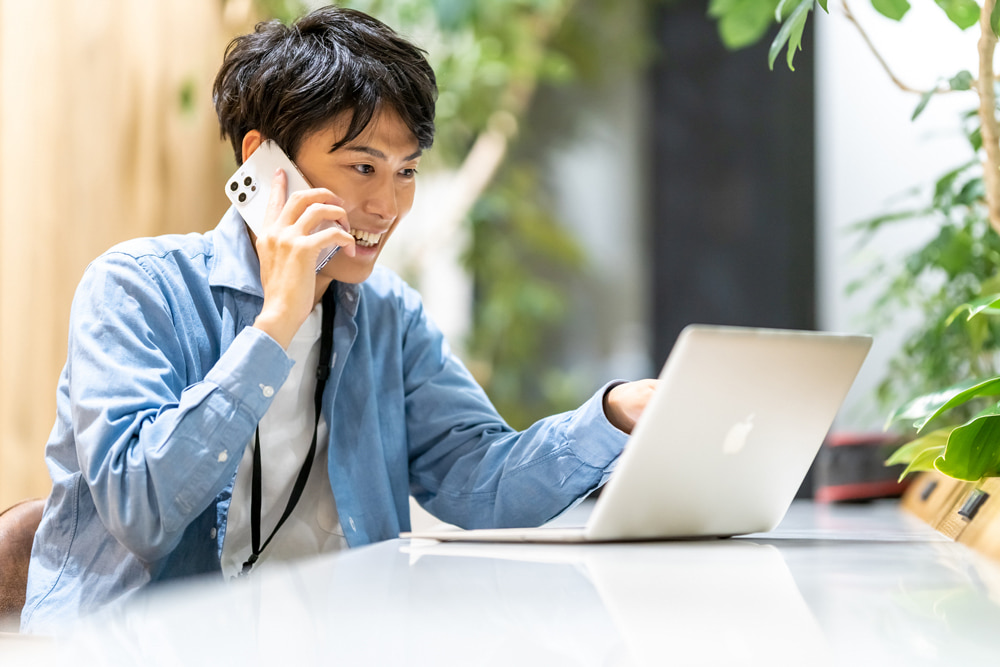 シェアオフィスで電話をする男性